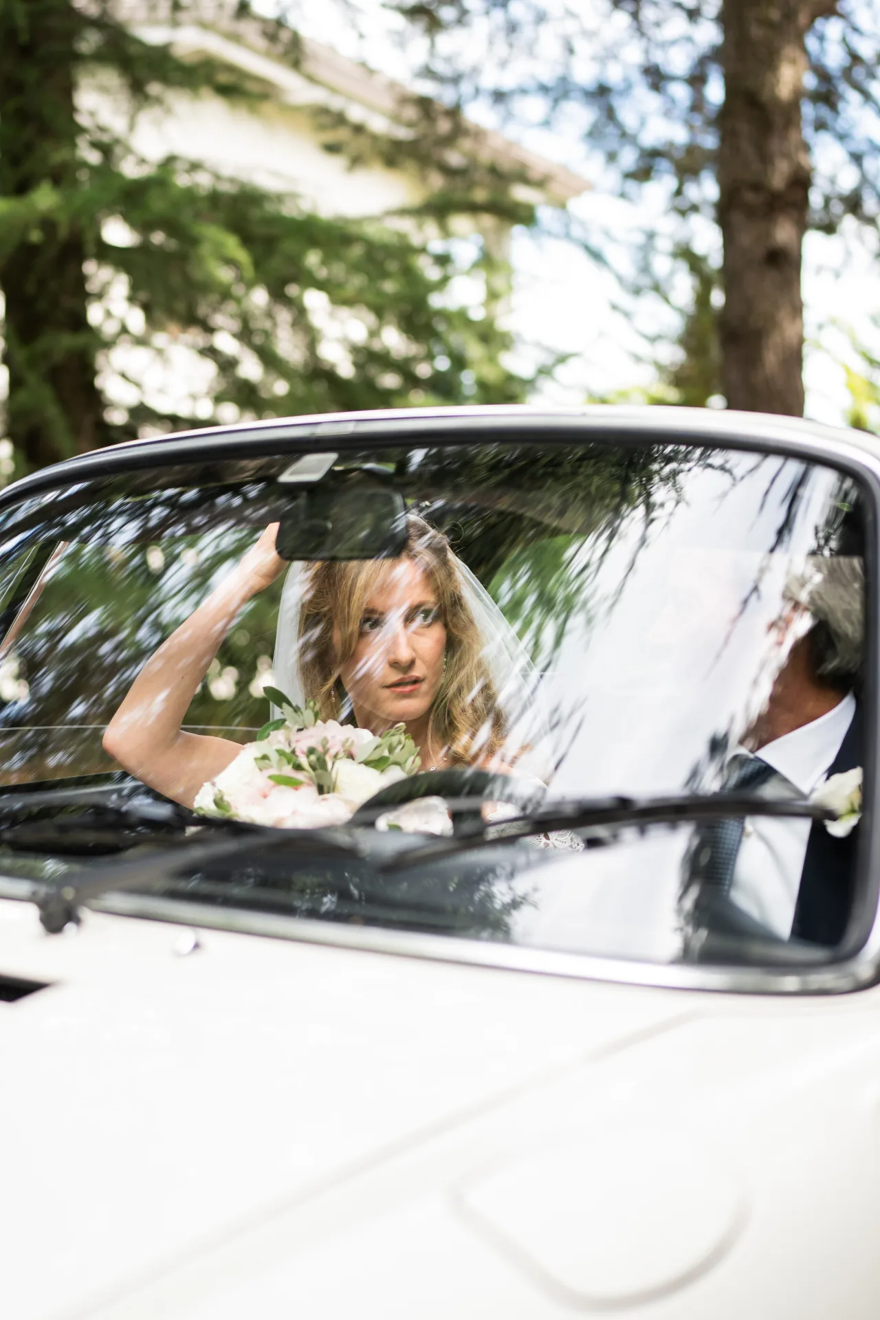 La sposa nell'auto, riflessi tra gli alberi